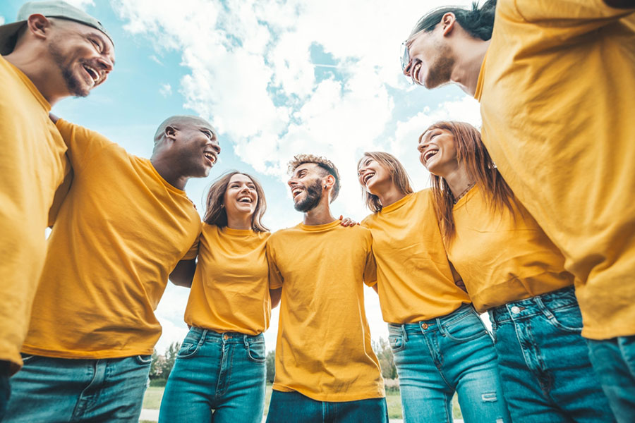 Groupe de personnes portant un t-shirt jaune et un jean bleu, souriant.