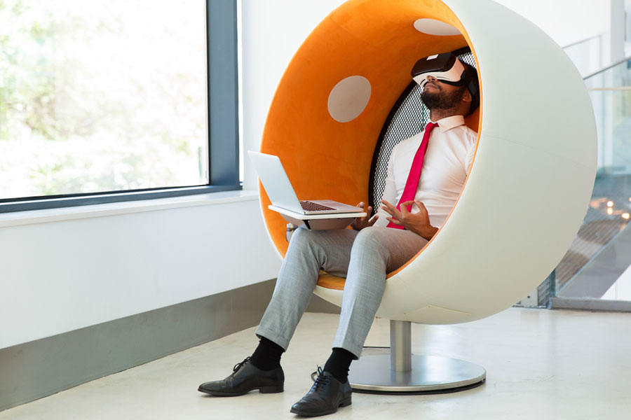 Un homme d'affaire avec un ordi entrain de décompresser avec un casque de réalité virtuelle